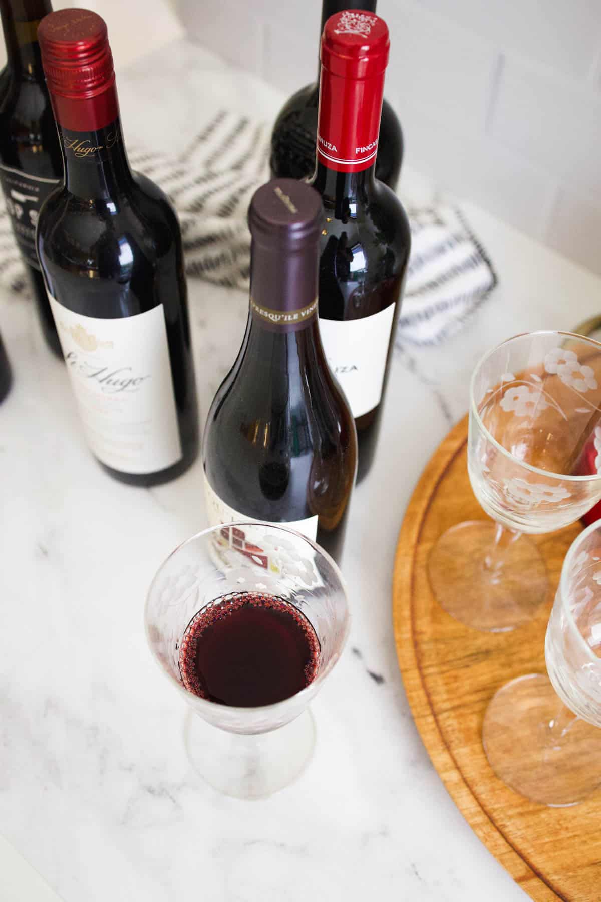 Overhead shot of a wine glass holding red wine and other bottles of wine.