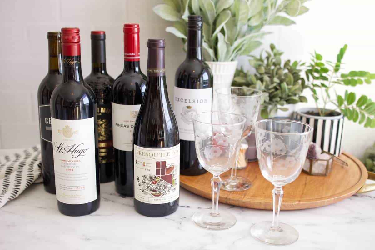 Bottles of red wine next to wine glasses on a table.