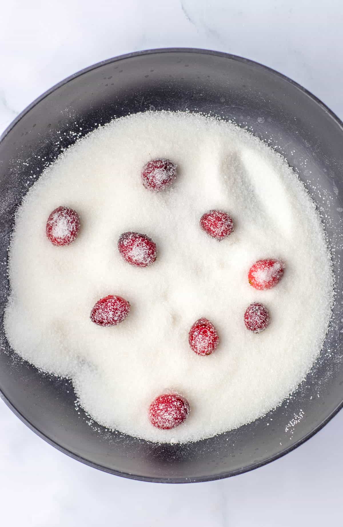 A bowl of sugar with cranberries in it.