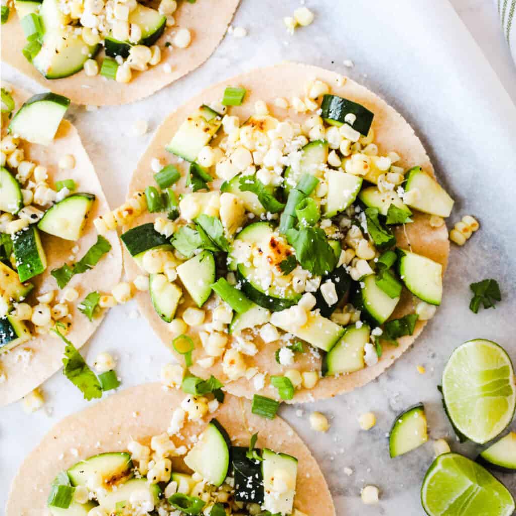 Zucchini and corn tostada with cotija cheese, green onions, and fresh lime juice.