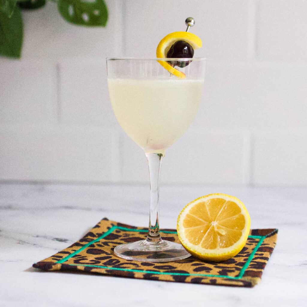 Gin sour garnished with a lemon twist and cherry.
