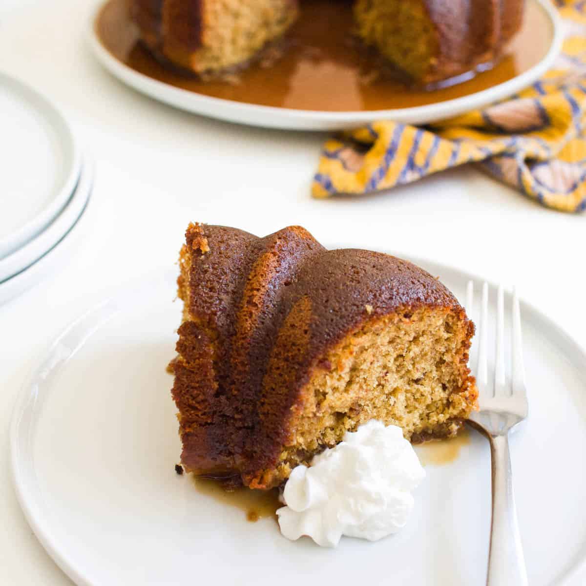 Bourbon bundt cake slice on a white plate with the cake in the background.