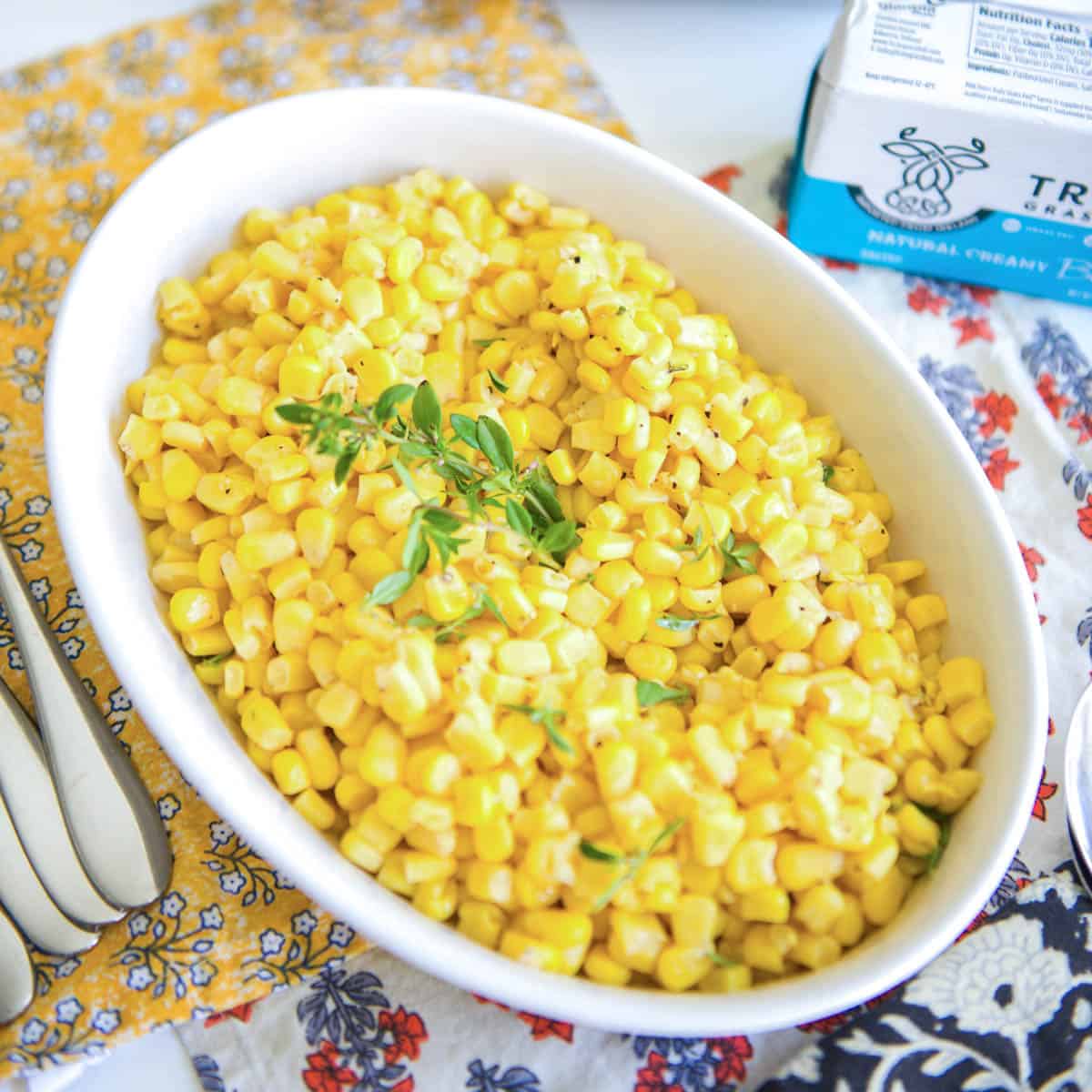 Corn in a white serving dish on a table.