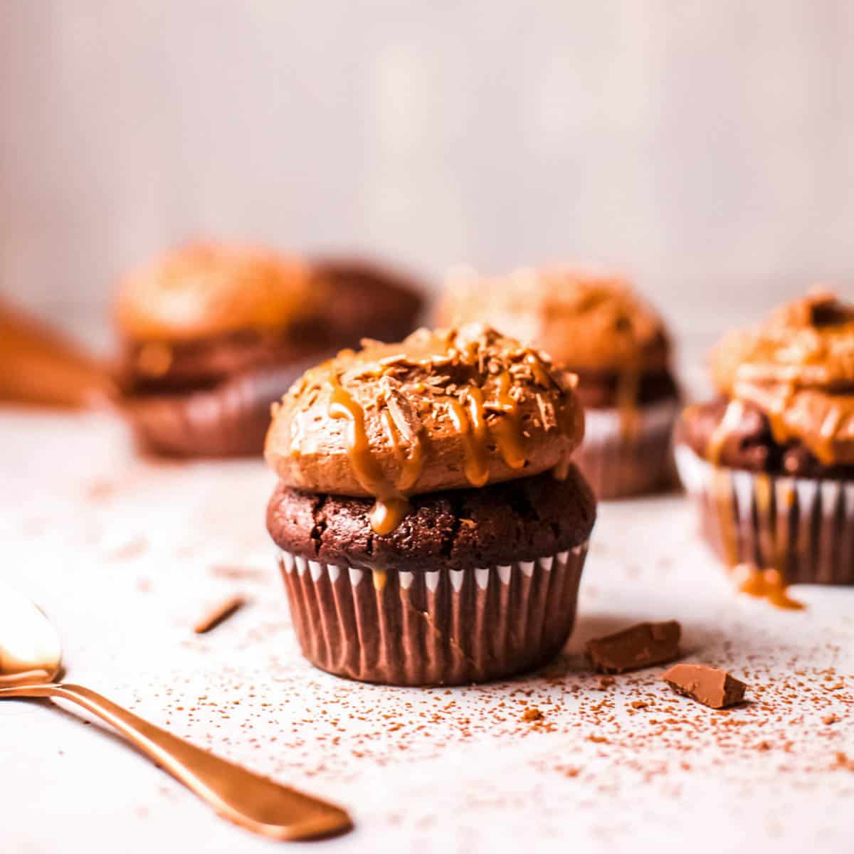 Chocolate frosted cupcakes on a table with a fork in the foreground.