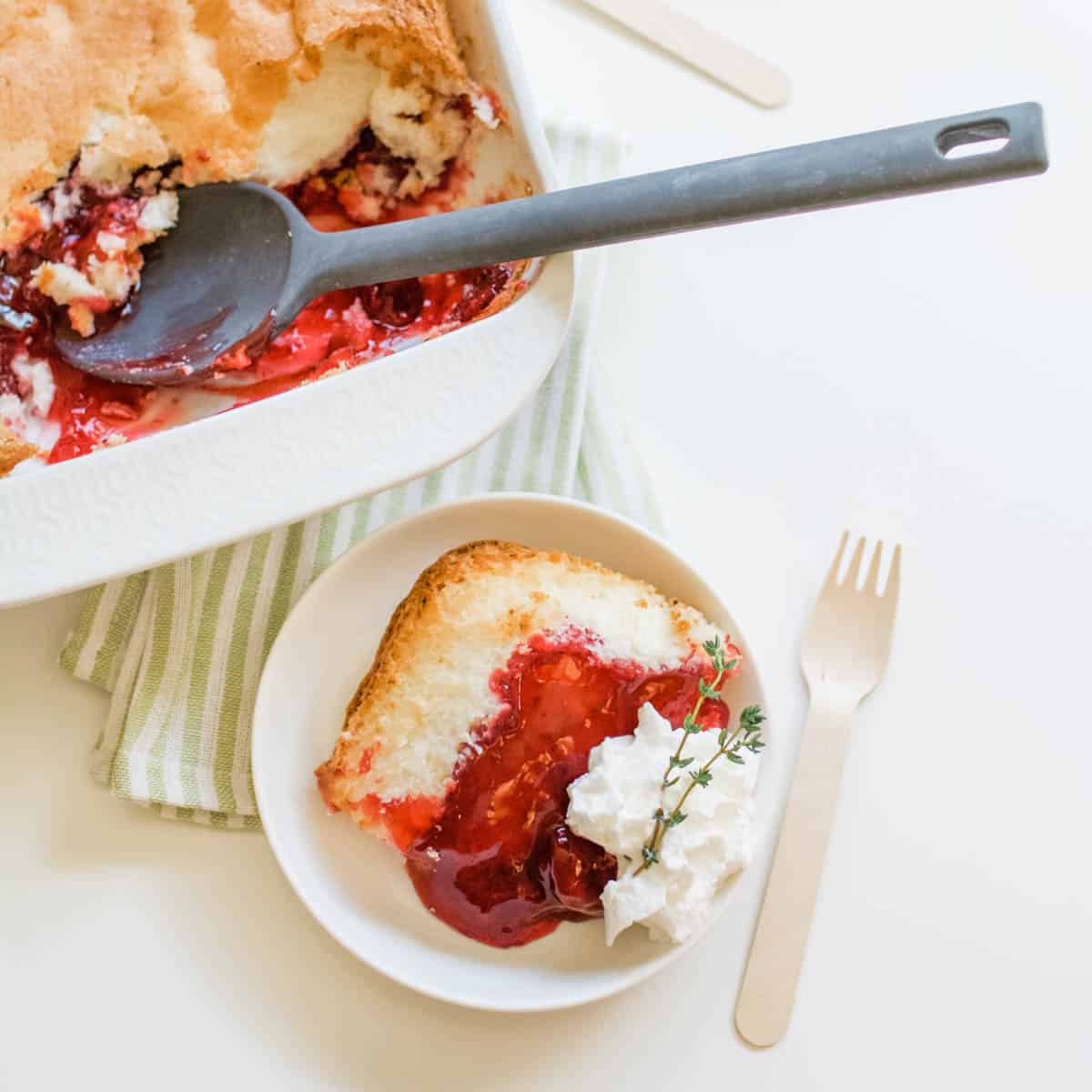 Strawberry shortcake dump cake in a baking dish with a white dessert plate and serving of the cake.