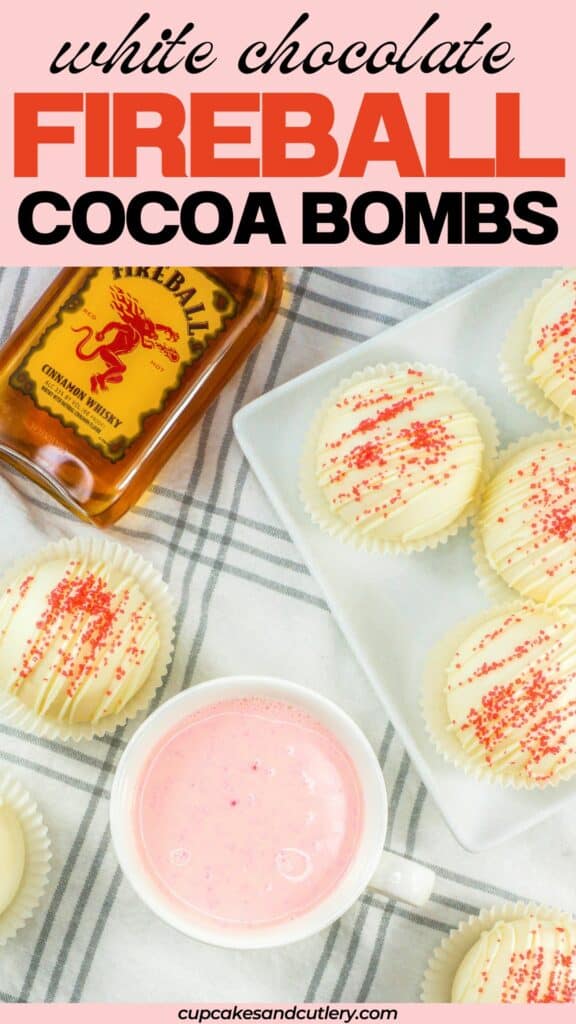 Close up of Fireball Hot Chocolate Bombs with a mug of pink hot chocolate and a bottle of Fireball.