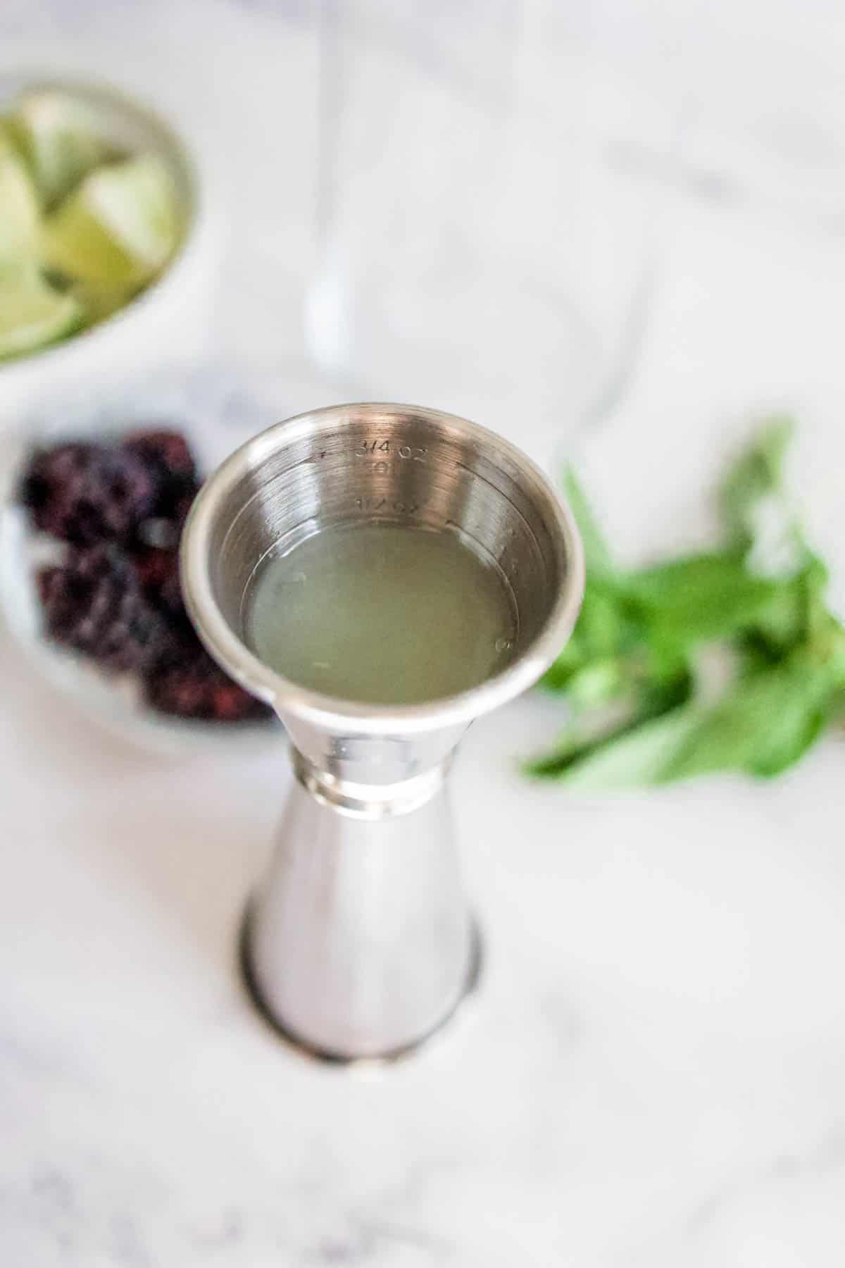 lime juice Cocktail jigger filled with fresh lime juice.