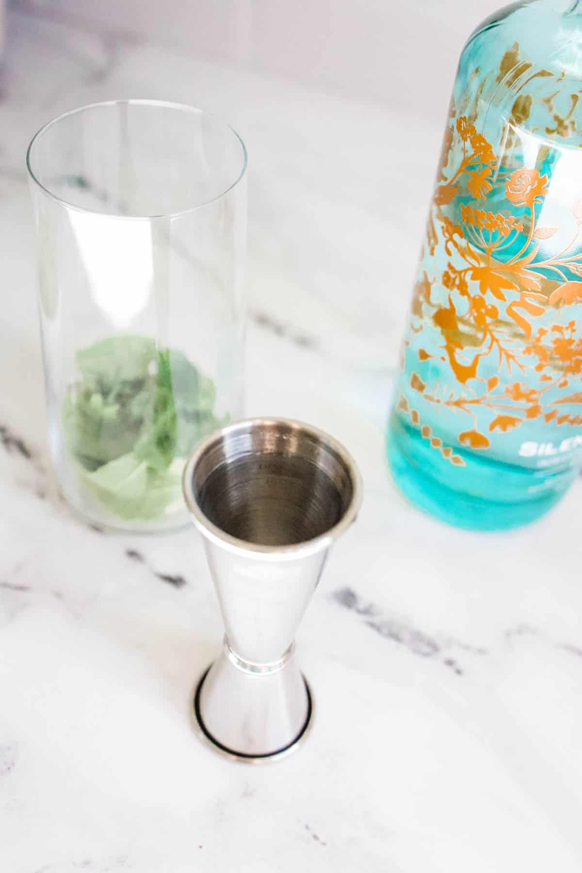 gin with fresh mint and lime Gin being measured into a glass with fresh mint and lime.