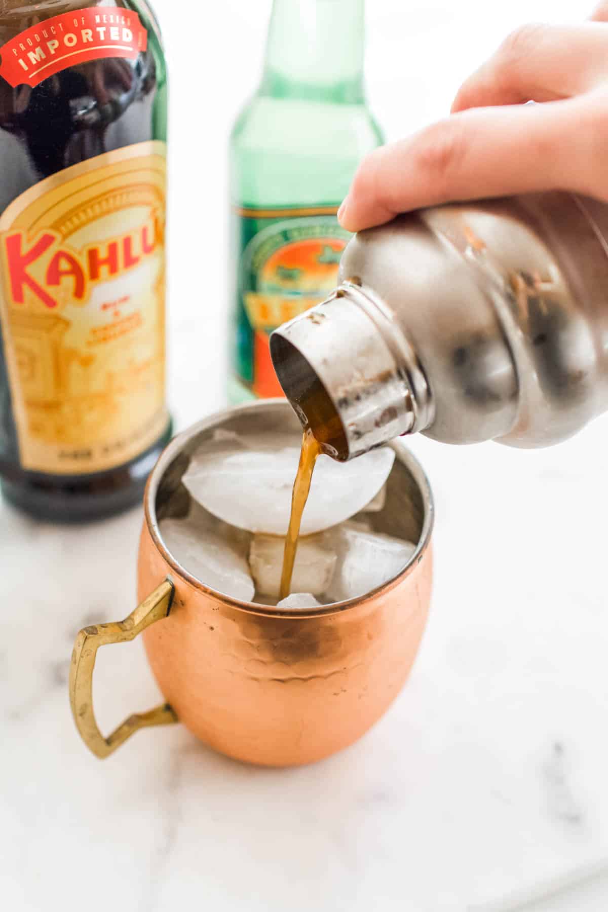 Cocktail being strained into a copper mug.