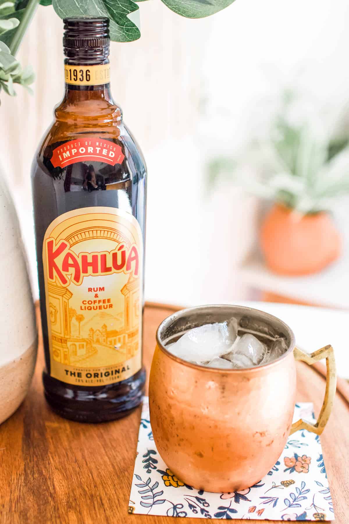 Moscow Mule in a mug on a table next to a bottle of Kahlua.