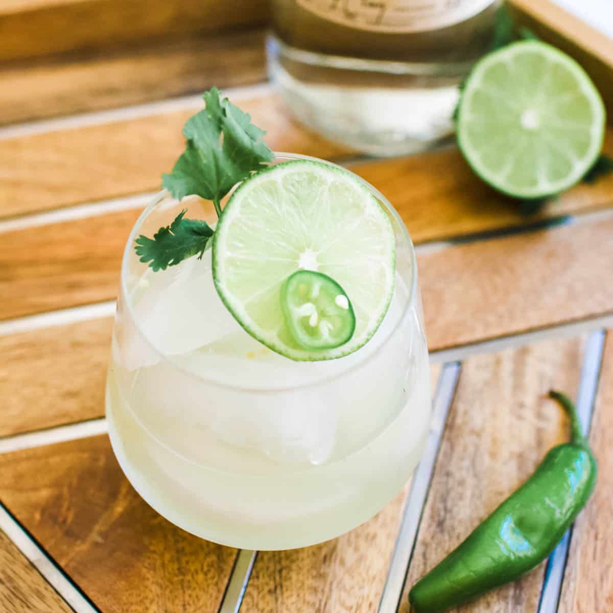 Serrano margarita on a tray next to a serrano pepper.