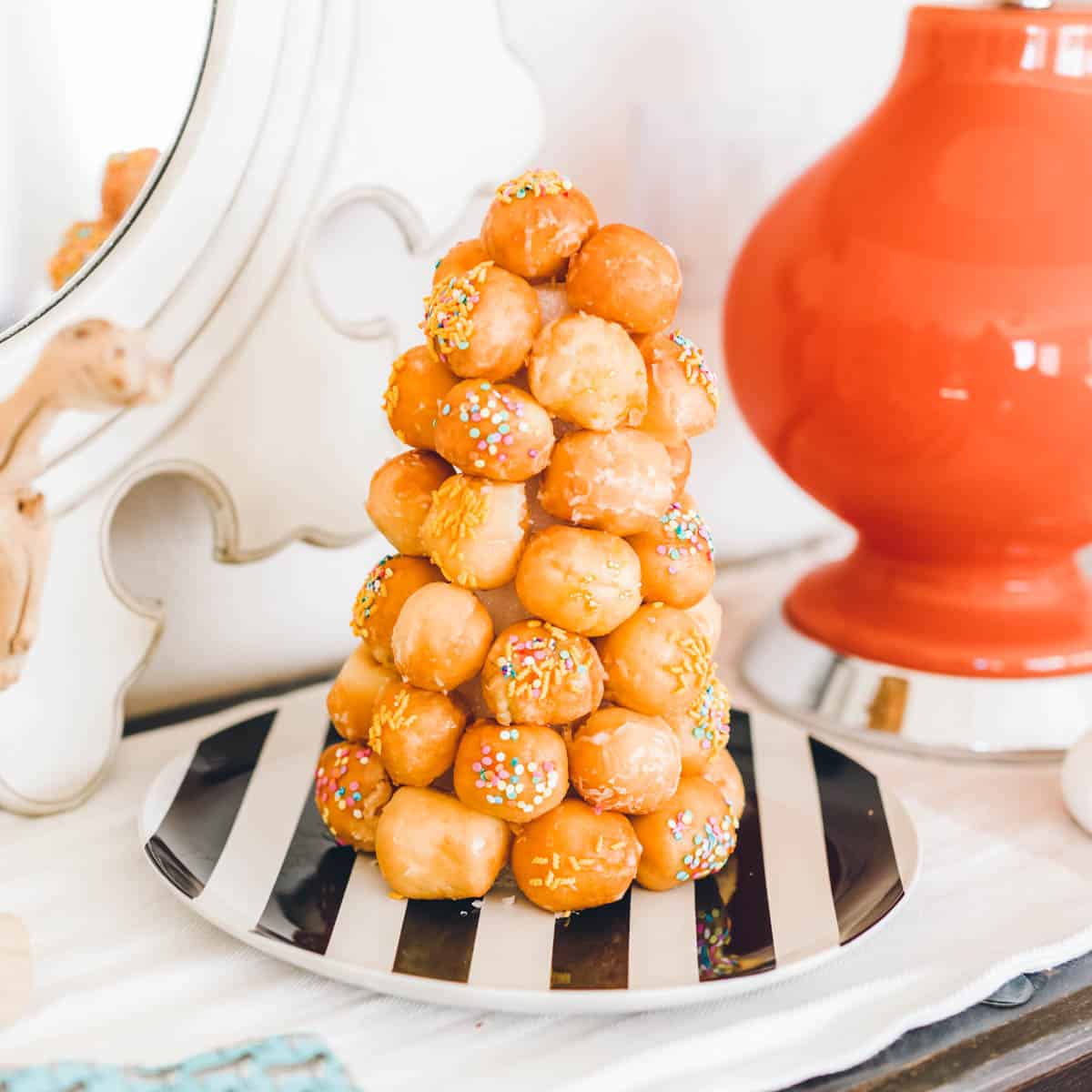 Donut tower on a black and white striped plate on a table. 