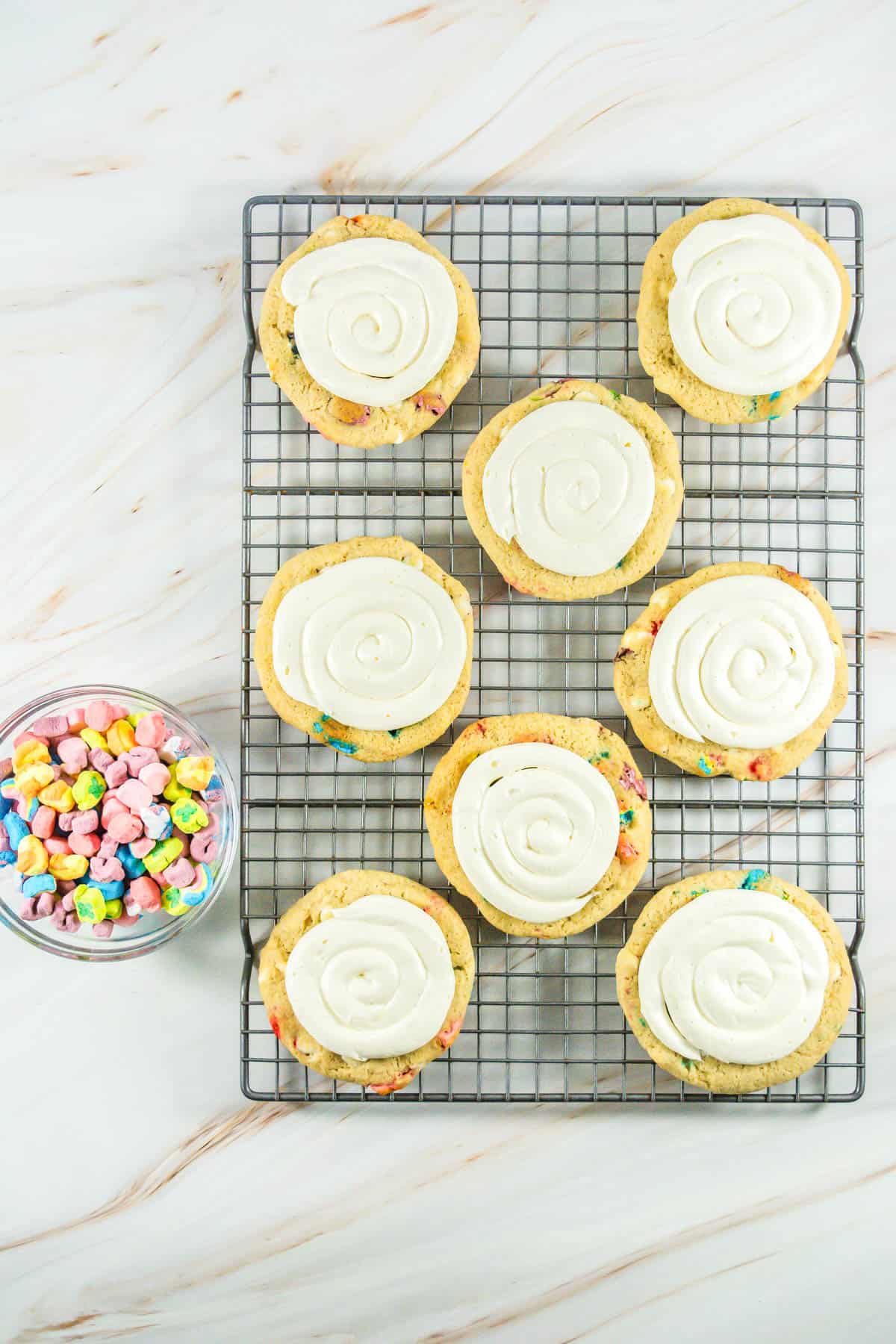 Lucky Charms Cookies on a cooling rack with frosting.