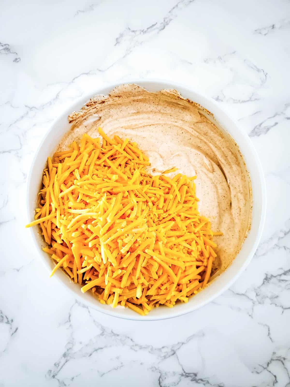 Add cheddar cheese into the taco seasoning and sour cream mixture.