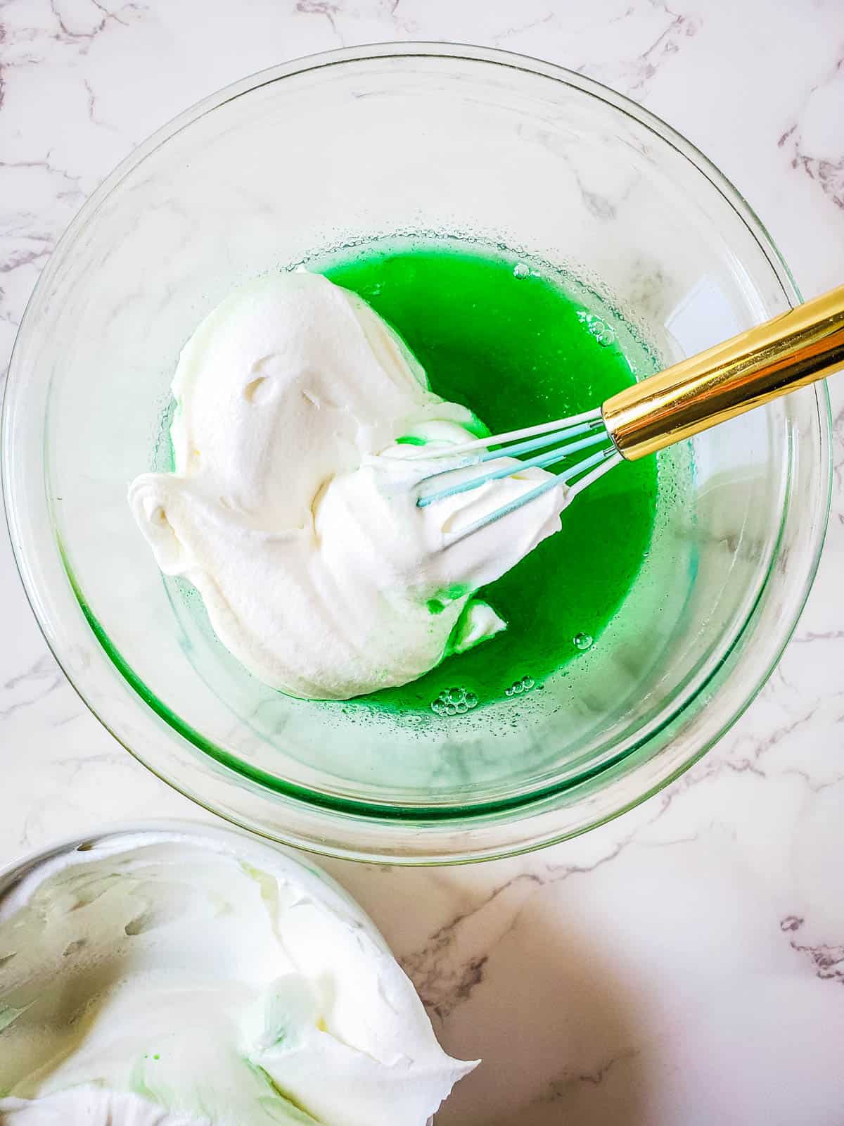 Whisking the whipped topping with the lime gelatin in a bowl.