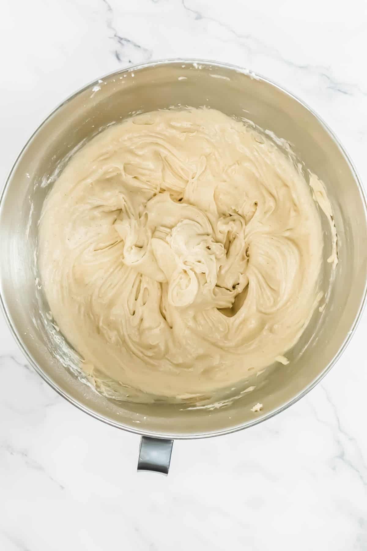 Smooth RumChata cupcakes frosting in the bowl of a stand mixer.