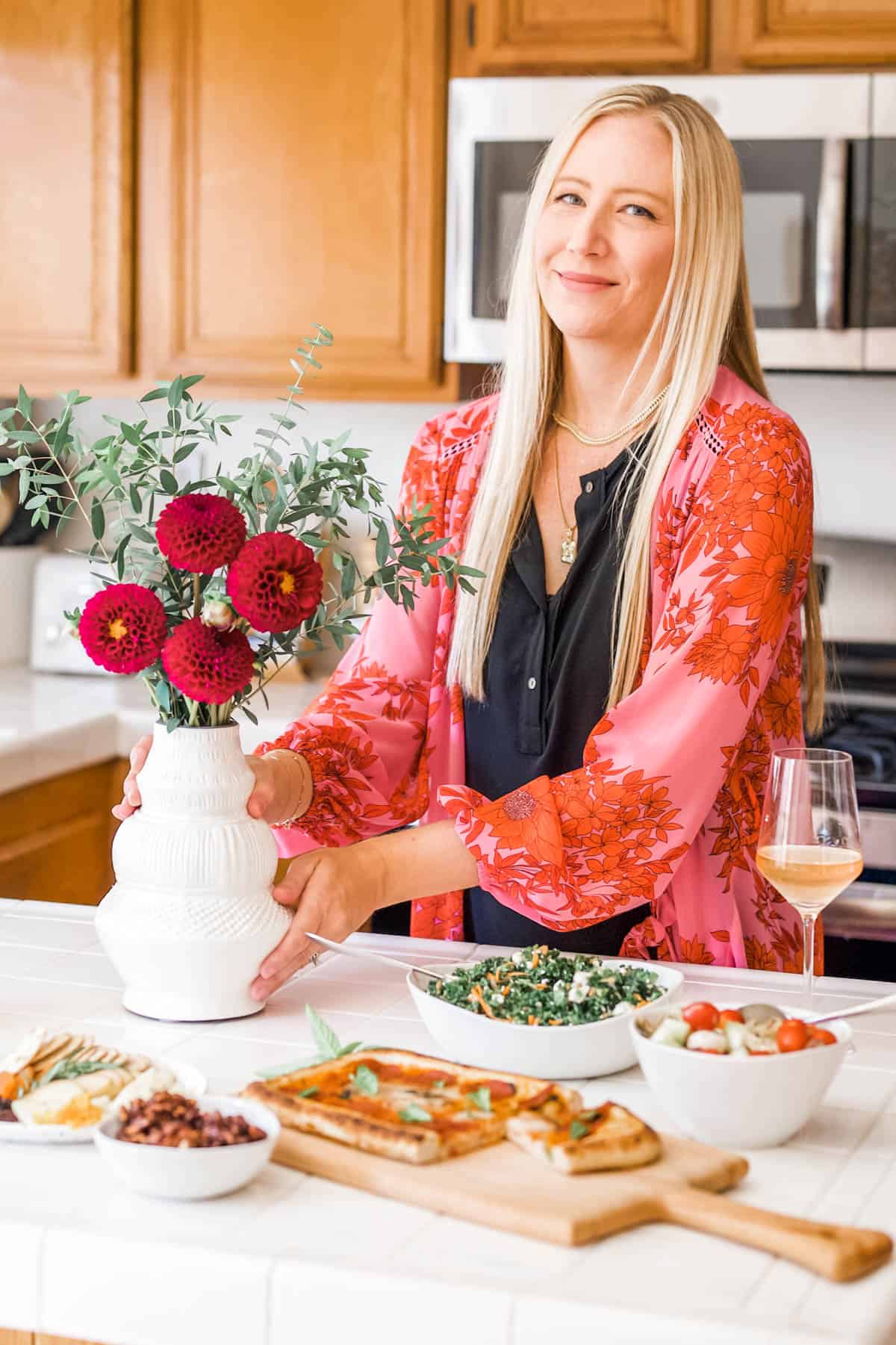 Sharon Garofalow setting down a vase of flowers on the counter.