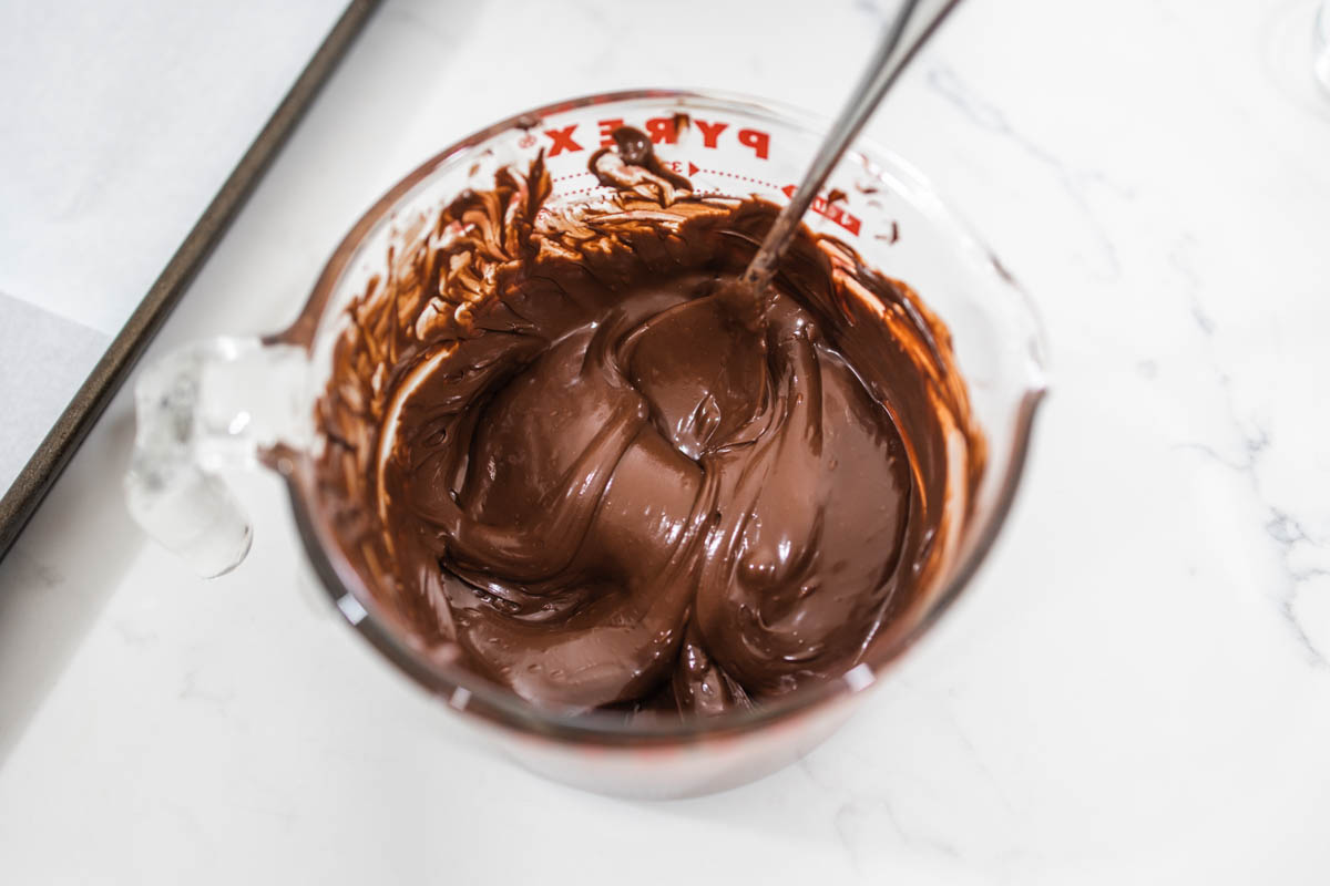 Melted chocolate Melted chocolate in a microwave-safe glass measuring cup with a spoon.