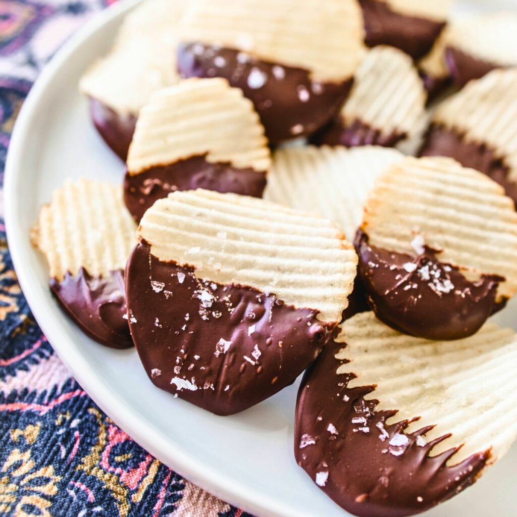 Sea salt on top of potato chip covered in chocolate on a plate for serving.