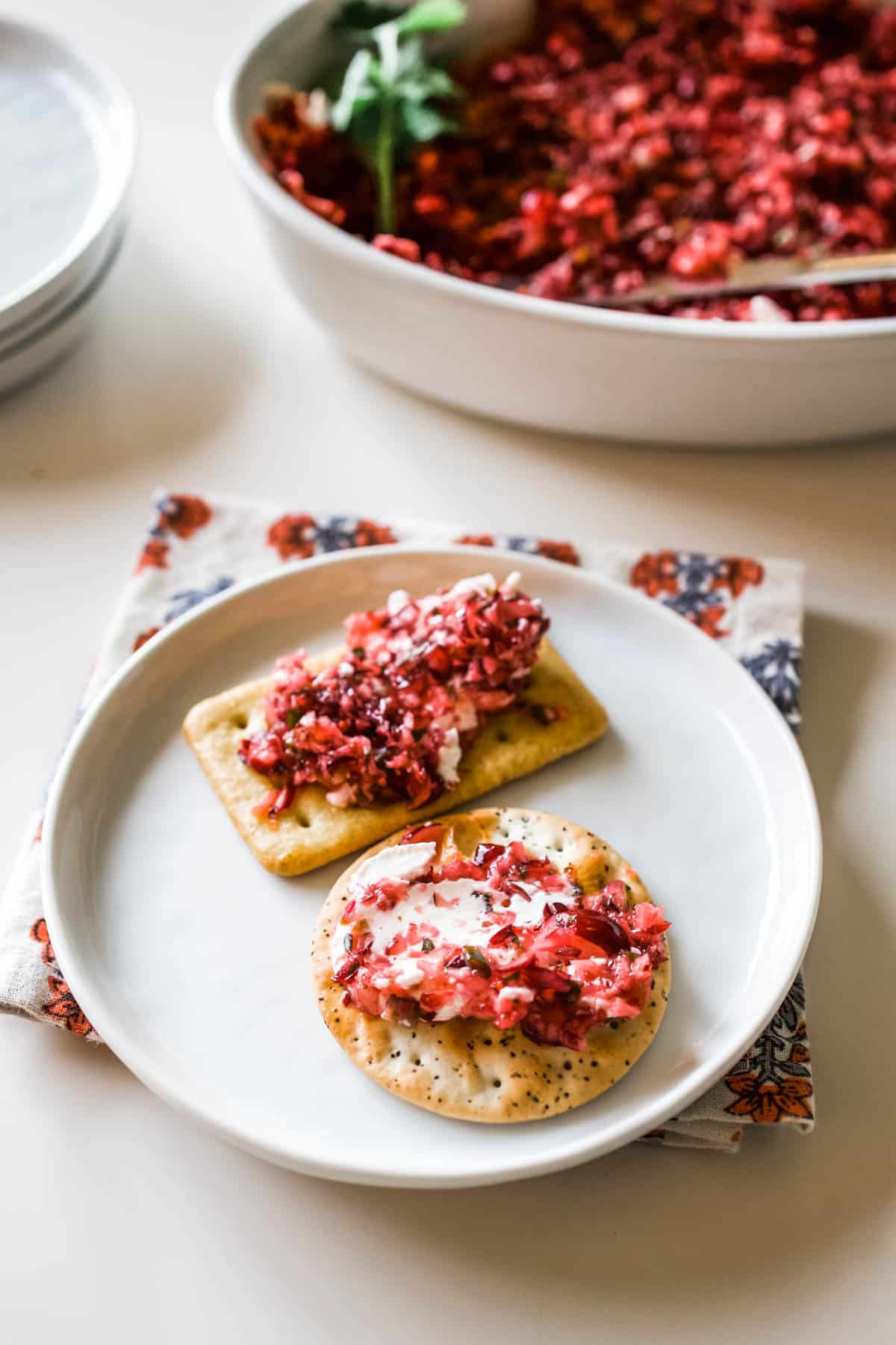 Crackers with Cranberry Jalapeno Dip Crackers topped with cream cheese cranberry jalapeno dip on a small white appetizer plate.