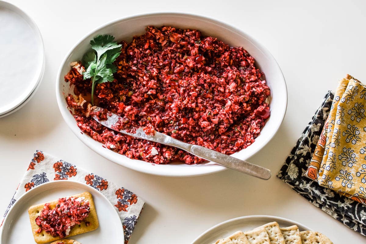jalapeno cranberry dip White bowl with cream cheese and jalapeno cranberry dip on a table.