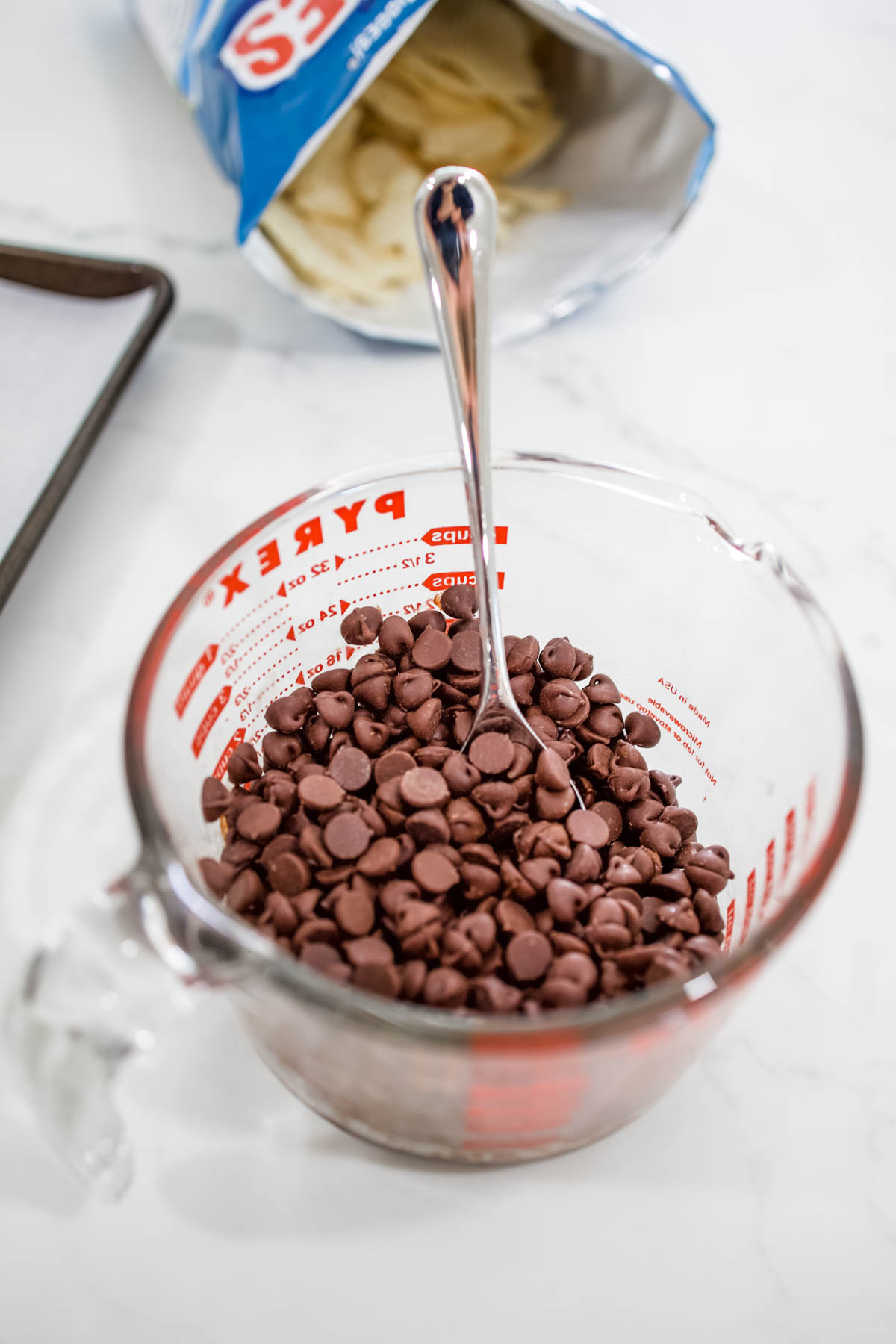 Unmelted chocolate chips Unmelted chocolate chips in a glass measuring cup with a spoon.