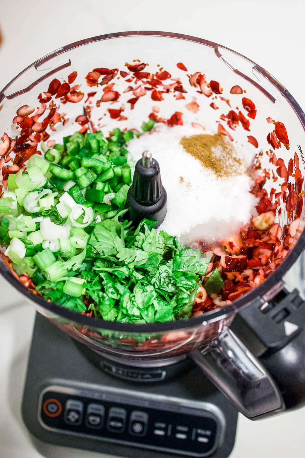 chopped ingredients The bowl of a food processor with chopped ingredients to make a jalapeno cranberry dip.